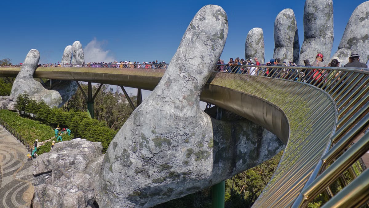 The iconic Golden Bridge with giant hand sculptures at Ba Na Hills, Vietnam, under a clear blue sky.